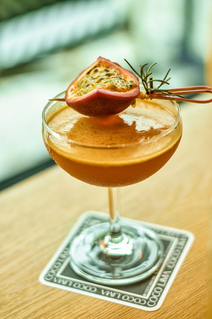 A stylish glass of passion fruit cocktail with garnish on a coaster. Perfect for summer vibes.