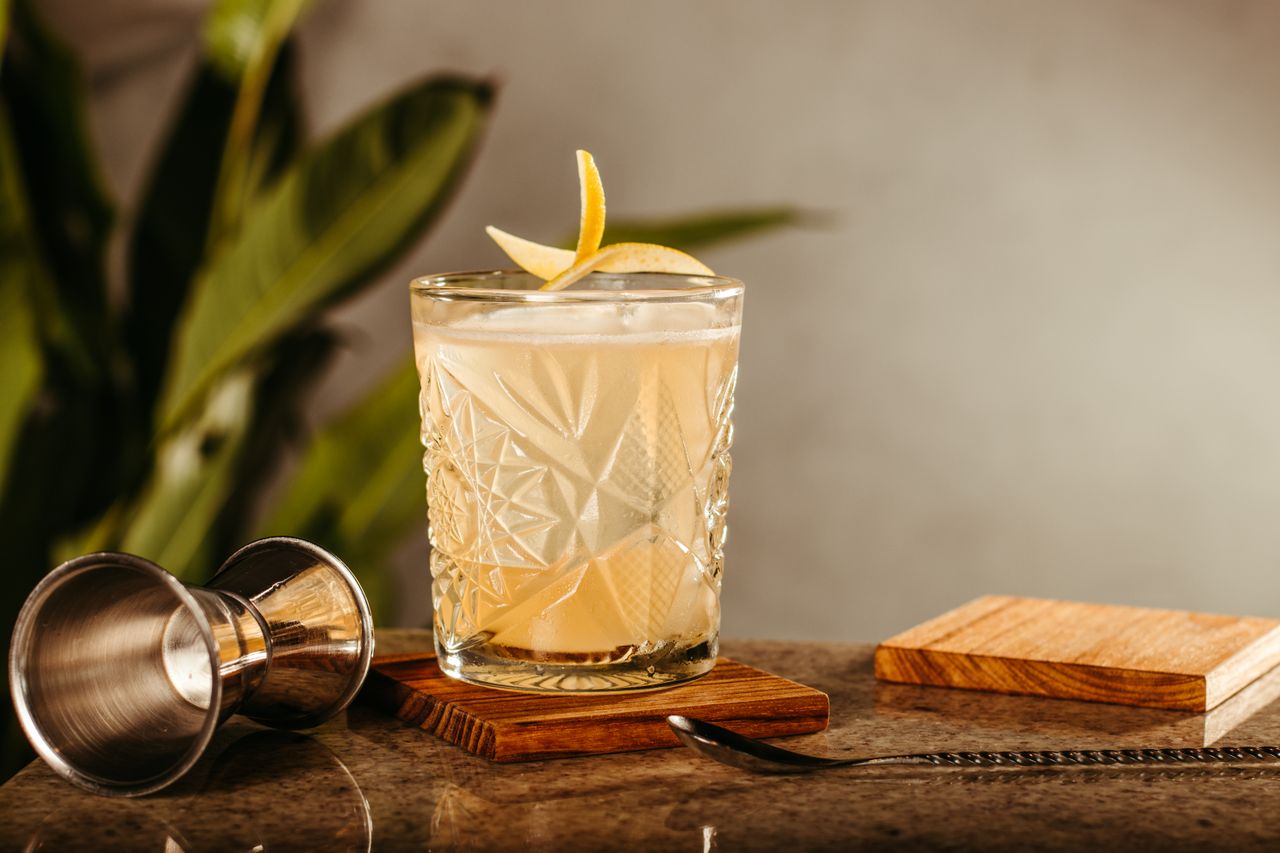 Elegant cocktail with lemon garnish on a rustic bar counter, perfect for a bistro vibe.